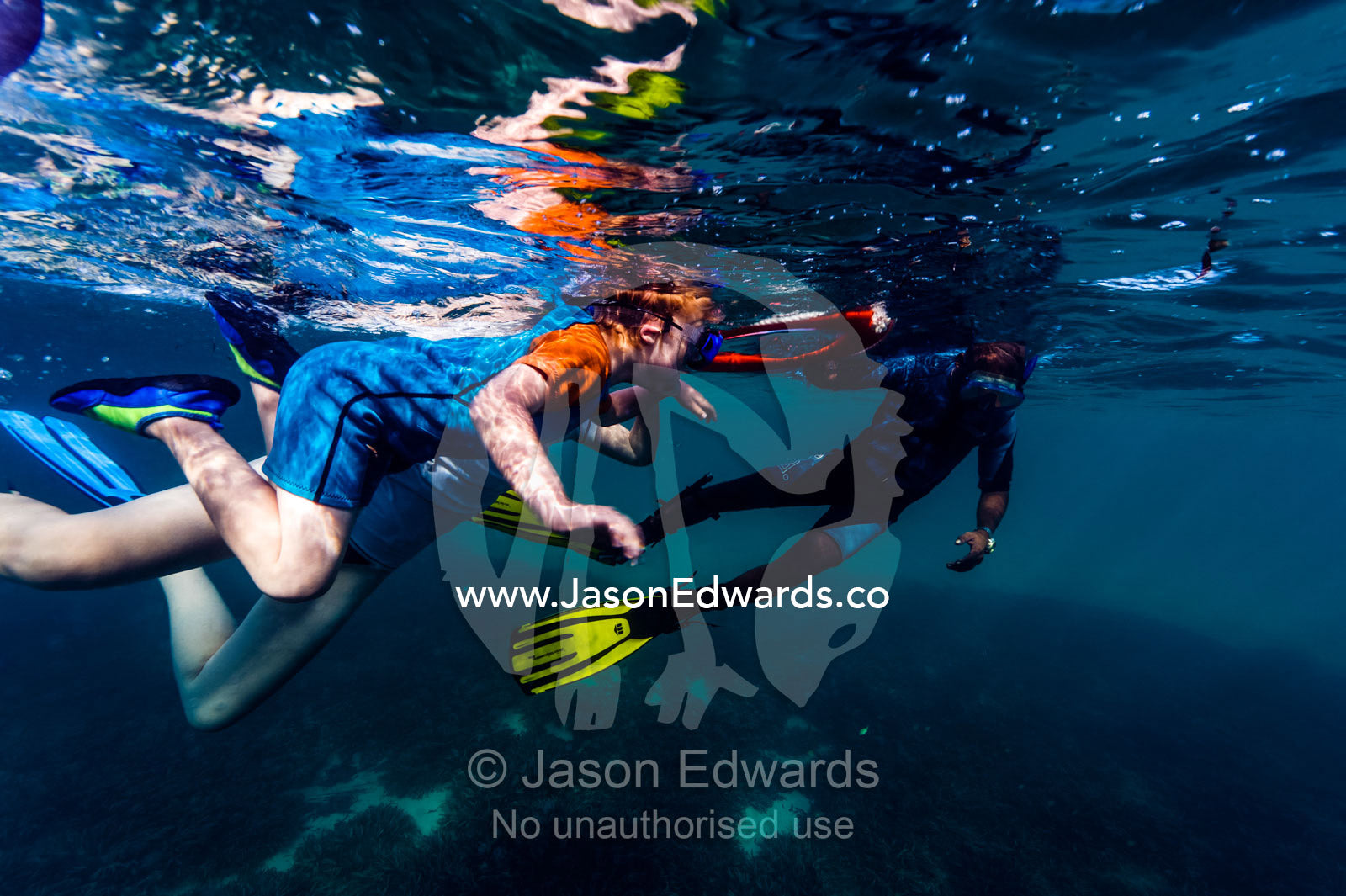 A scuba diving instructor assists a small boy to snorkel over a tropical coral reef using a floating rescue ring. Bwejuu, Blue Lagoon Reef, Unguja Island, Zanzibar, Tanzania.