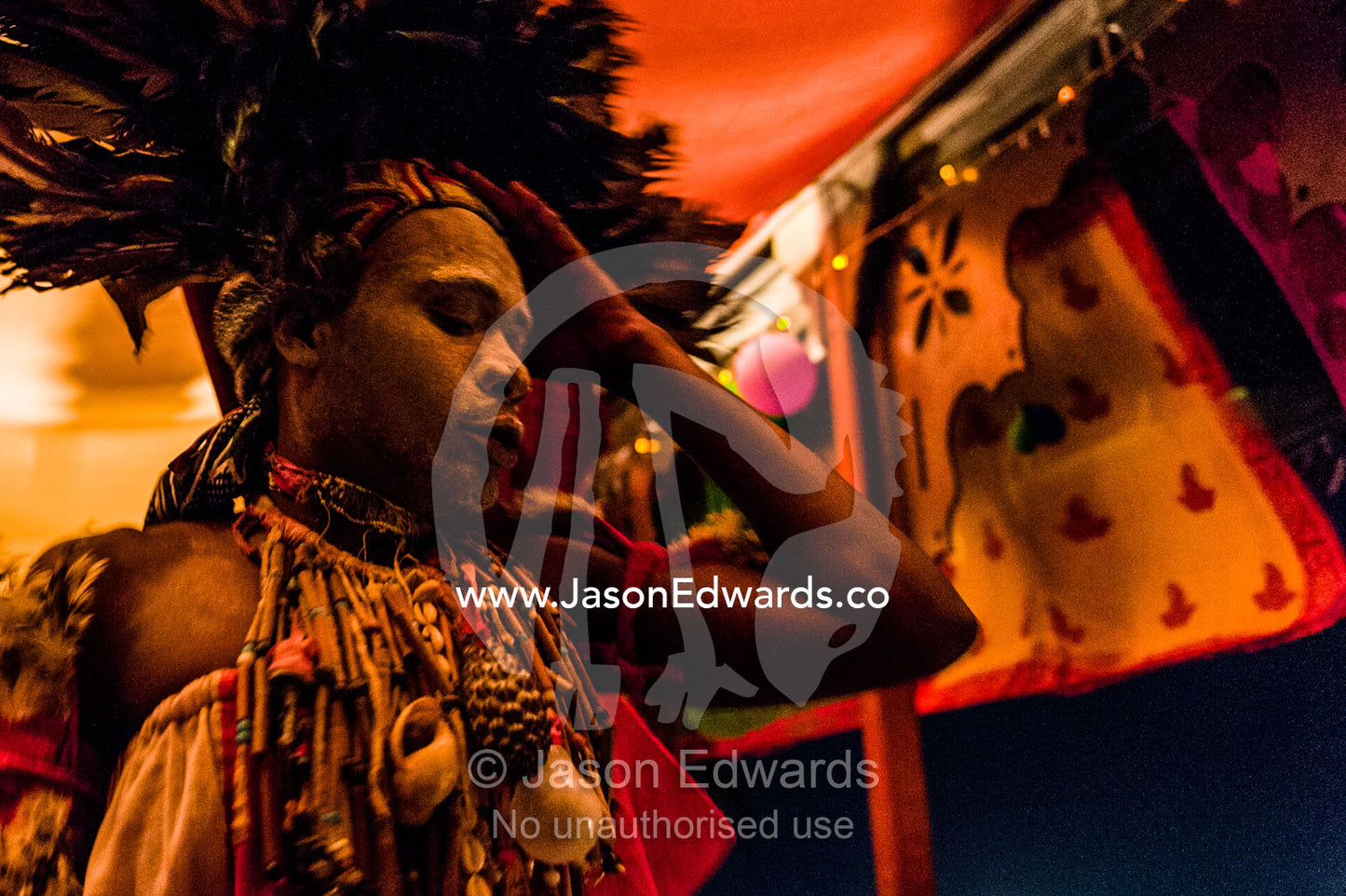 A Spirit dancer decorated in facial paint, shells, beads and a feathered headdress performing at a rooftop restaurant at night. Stone Town, Mji Mkongwe, Zanzibar, Unguja Island, Zanzibar, Tanzania.