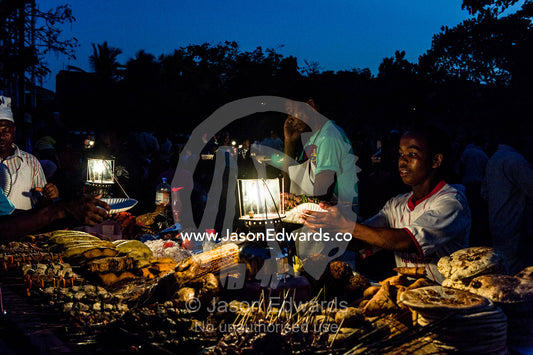 Food stall vendors prepare fresh food for shoppers at a night market by the Indian Ocean. Forodhani Gardens, Stone Town, Mji Mkongwe, Zanzibar, Unguja Island, Zanzibar, Tanzania.