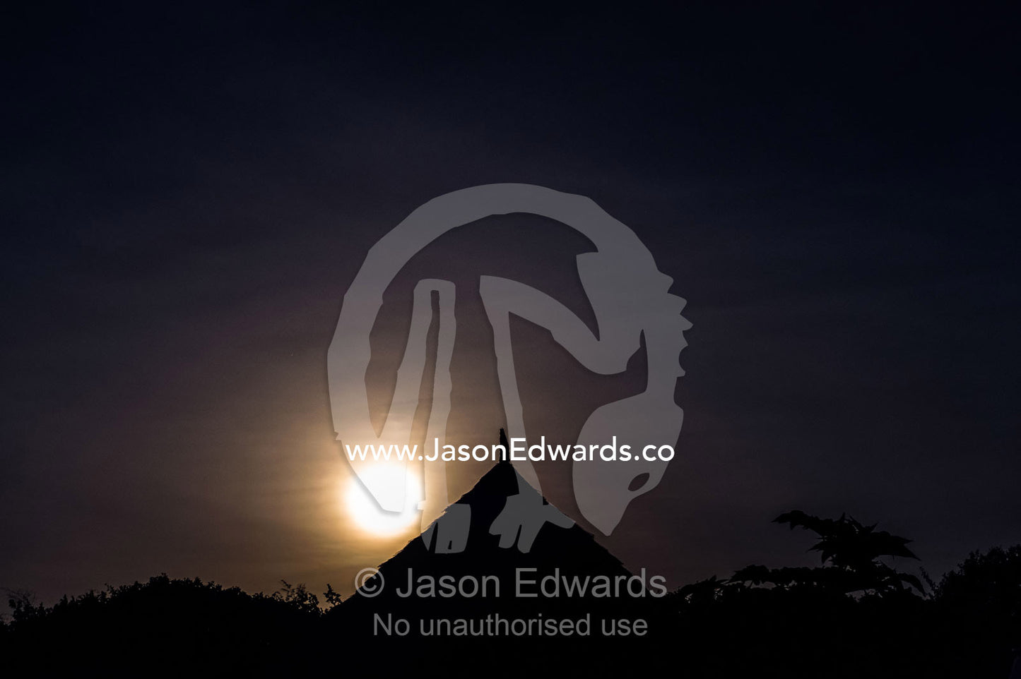 Moonrise over the pointed thatched roof of a hut in an African village. Karatu, Rhotia Valley Lodge, Rhotia Valley, Karatu District, Arusha Region, Tanzania.