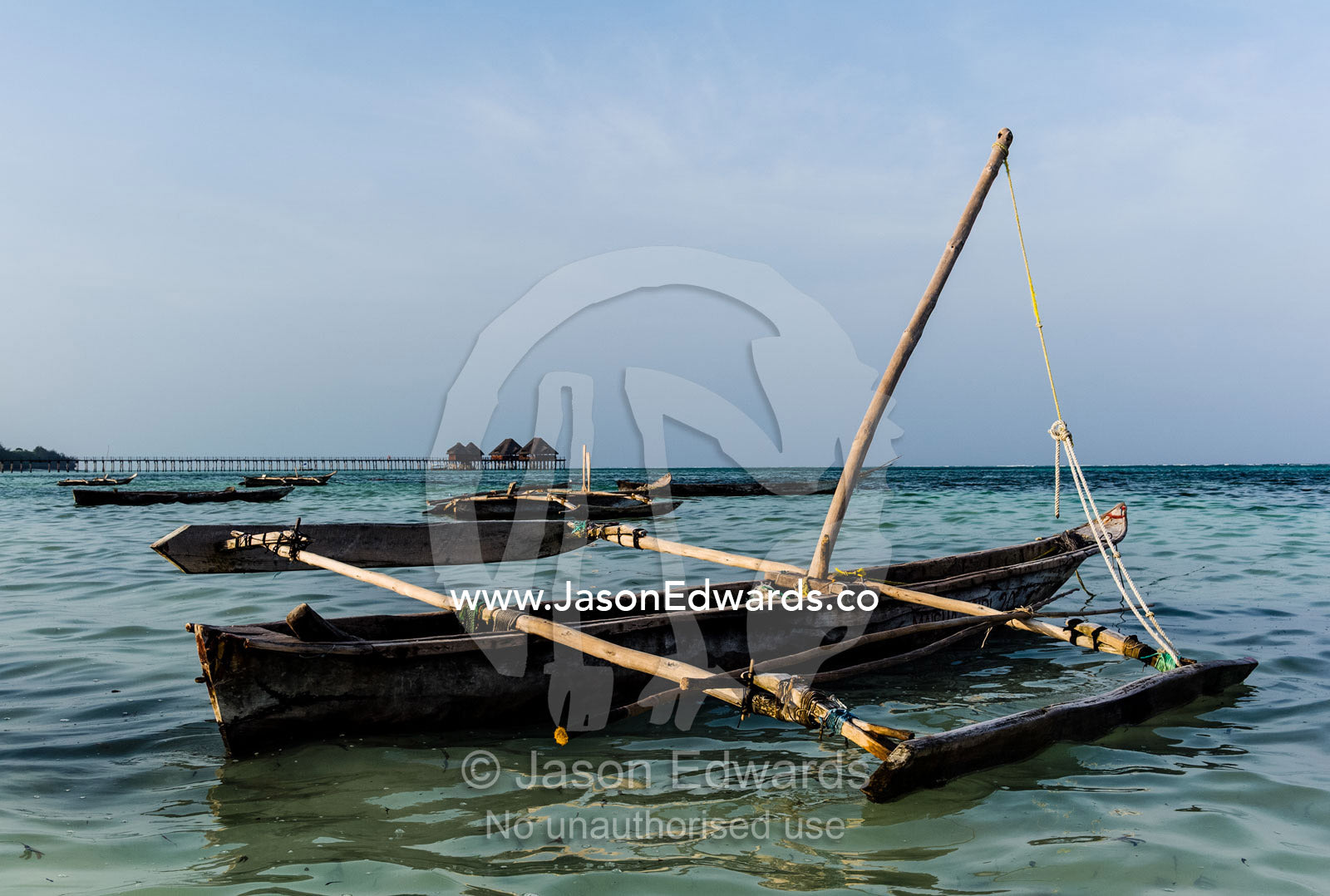 A small wooden fishing dhow moored in the shallows of a tropical island. Bwejuu, Unguja Island, Zanzibar, Tanzania.