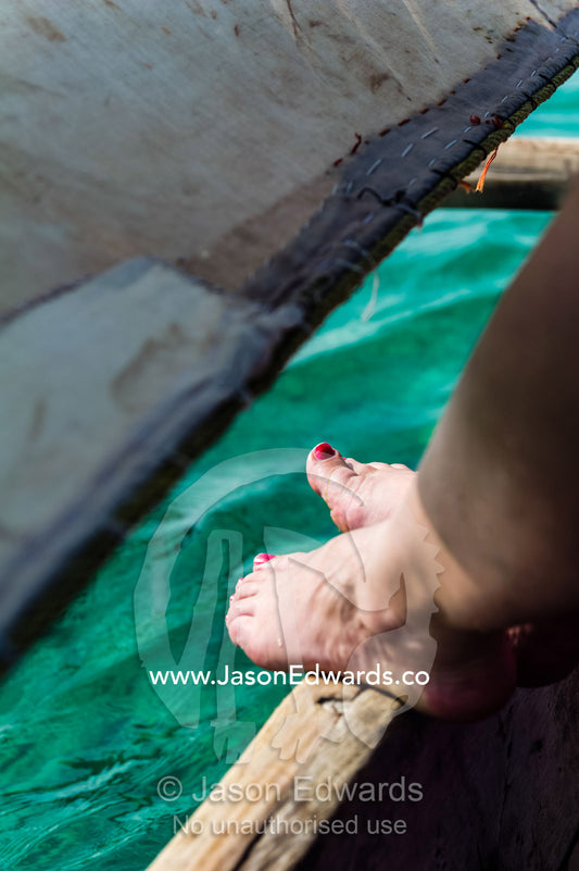Nail polish on the toes of a tourist sailing in a wooden fishing dhow. Bwejuu, Unguja Island, Zanzibar, Tanzania.