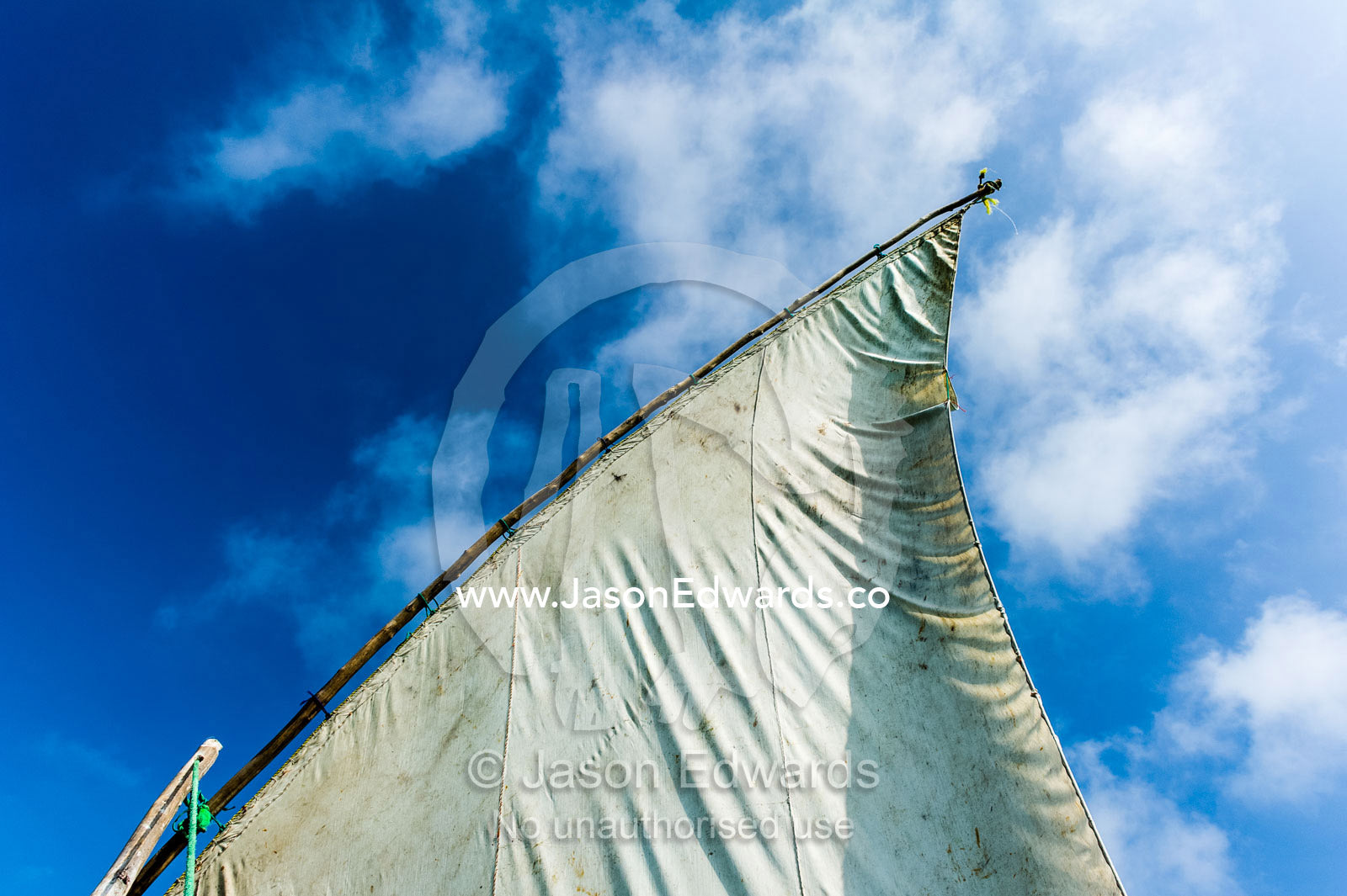 The tarpaulin sail and mast of a wooden dhow flapping in the breeze. Bwejuu, Unguja Island, Zanzibar, Tanzania.
