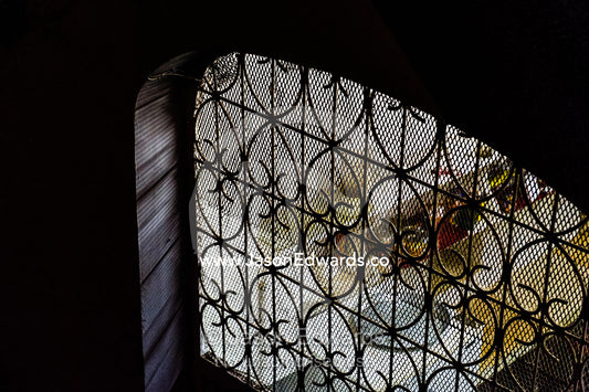 Looking through a barred and screened window into the kitchen of a home in a trading port at night. Stone Town, Mji Mkongwe, Zanzibar, Unguja Island, Zanzibar, Tanzania.