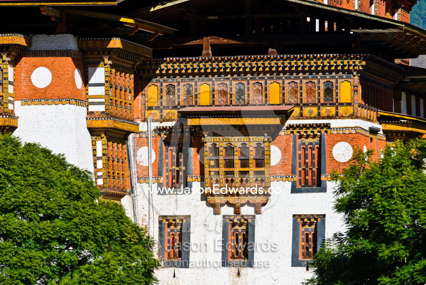 Ornately carved and painted window frames and balconies on an ancient Buddhist monastery facade. Punakha Dzong, Punakha dzongkhag, Punakha District, Bhutan.