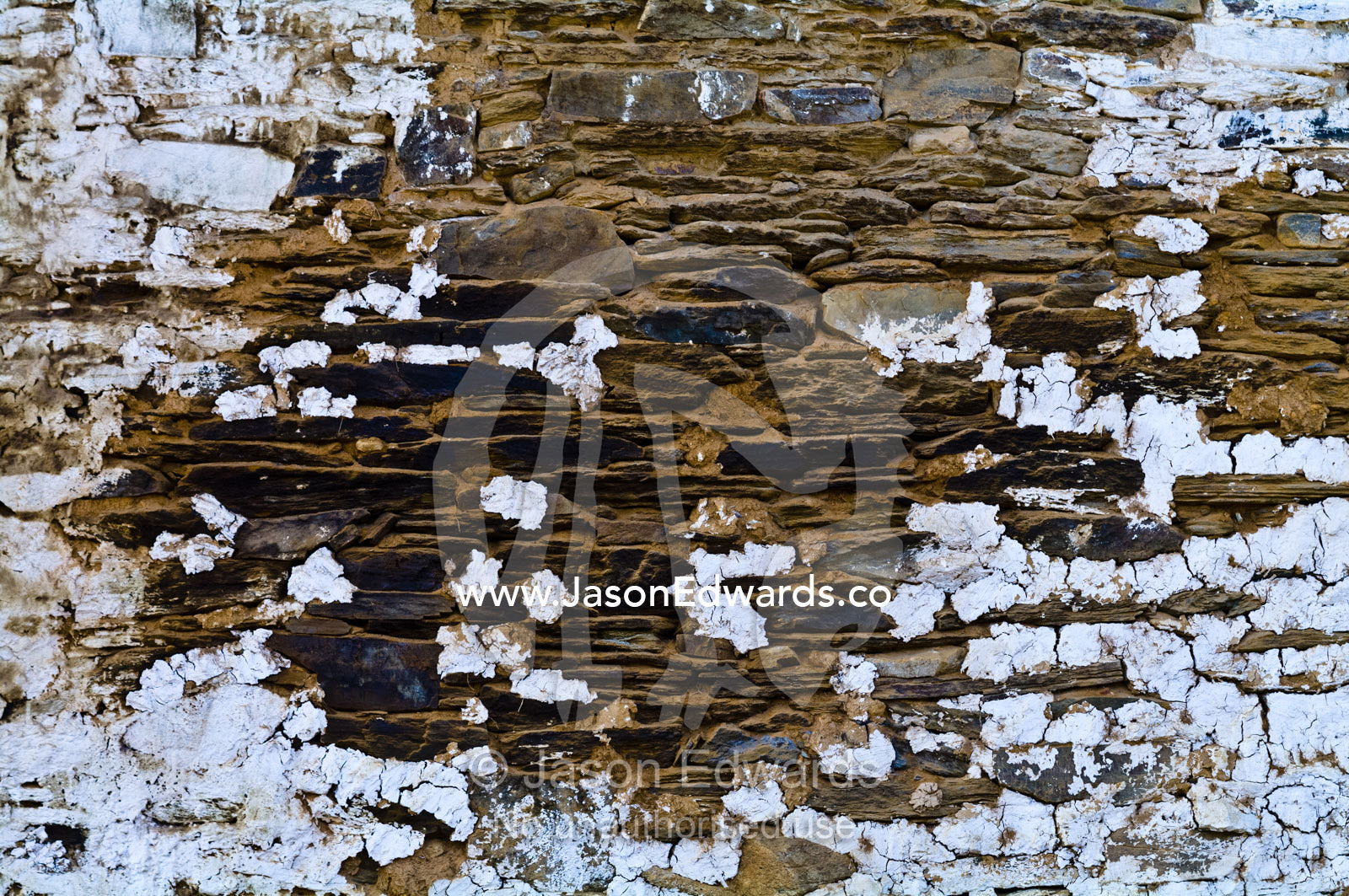 White-wash paint peeling from a weathered handmade stone tiled wall on an ancient Buddhist monastery wall. Gangteng Monastery, Ganteng, Wangdue Phodrang District, Phobjika Valley, Phobjikha Valley, Gangteng Valley, Black Mountains, Bhutan.