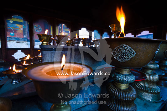 Flames burns serenely in large brass butter lamps in an ancient Buddhist monastery prayer room. Cheri Monastery, Chagri Dorjeden Monastery, Thimphu, Thimphu District, Bhutan.
