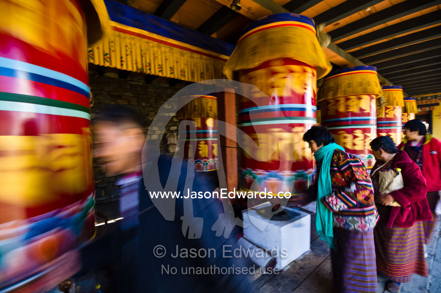 Buddhists march past colorful prayer wheels spinning them whilst making prayers and aspirations. Thimphu Memorial Chorten, Thimphu Bhutan.