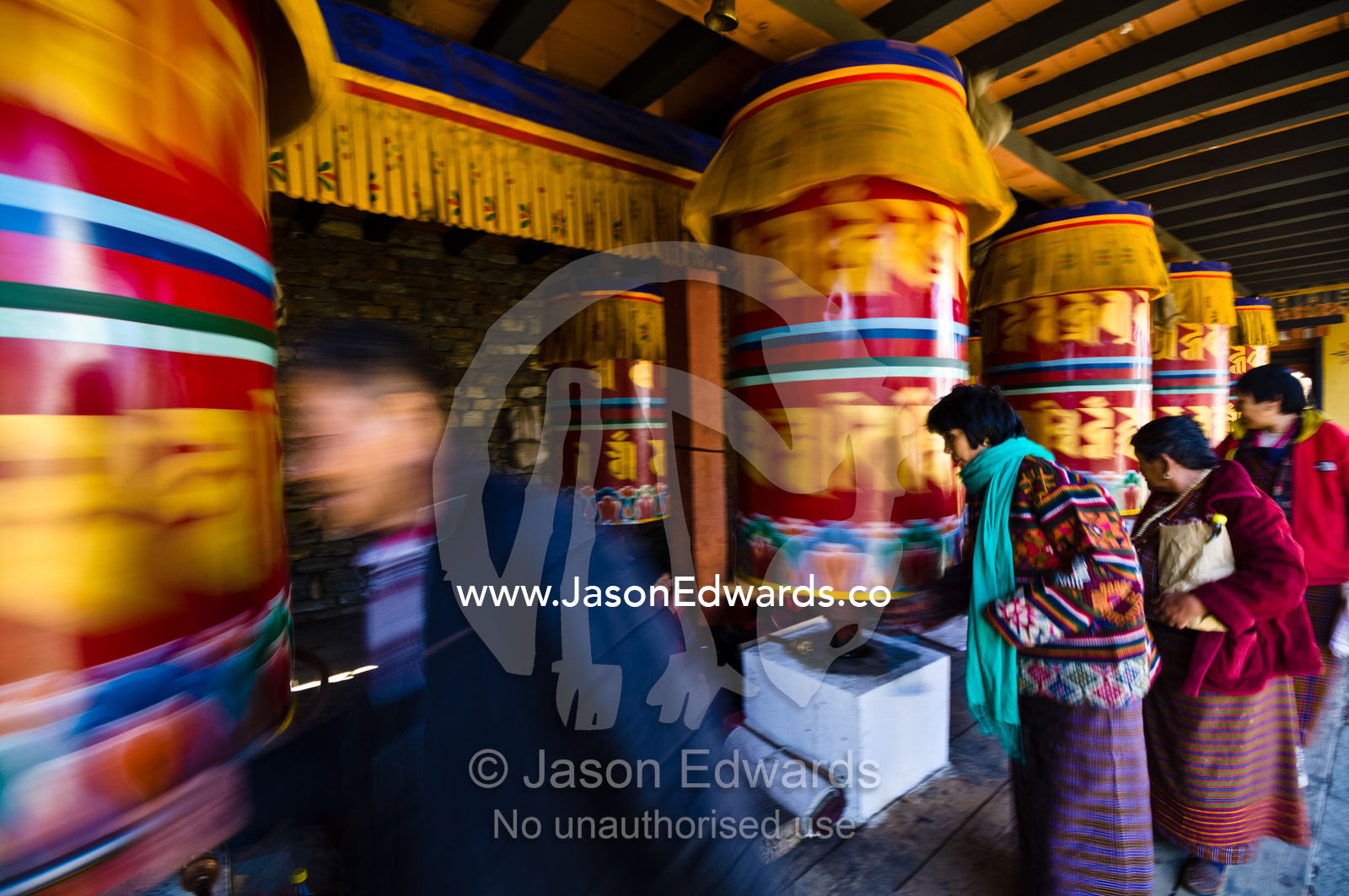 Buddhists march past colorful prayer wheels spinning them whilst making prayers and aspirations. Thimphu Memorial Chorten, Thimphu Bhutan.