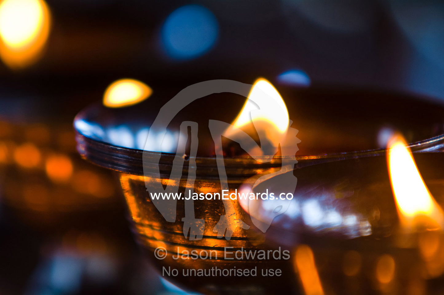 A candle flickers in a brass butter lamp in the prayer room of an ancient Buddhist monastery. Cheri Monastery, Chagri Dorjeden Monastery, Thimphu, Thimphu District, Bhutan.
