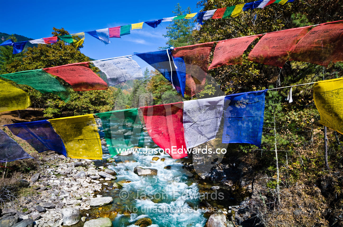 Colorful prayer flags fly over turquoise rapids in an alpine river. Thimphu Chu, Thimphu River, Thimphu, Thimphu District, Bhutan.
