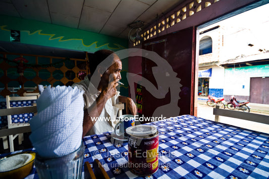 A retired poacher sits with a mug of coffee, dragging on cigarette in a Peruvian restaurant. Nauta, Amazon Basin, Loreto Region, Maynas Province, Peru.