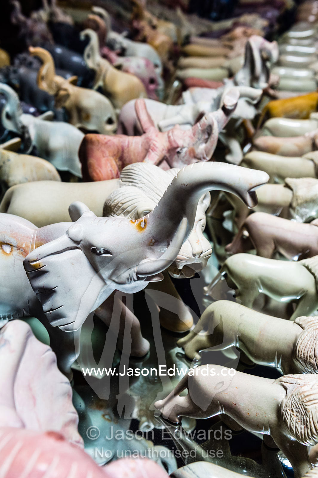 African Elephants, lions and other wildlife carved from soap stone for sale to tourists in a roadside stall. Maasai Mara National Reserve, Narok County, Kenya.