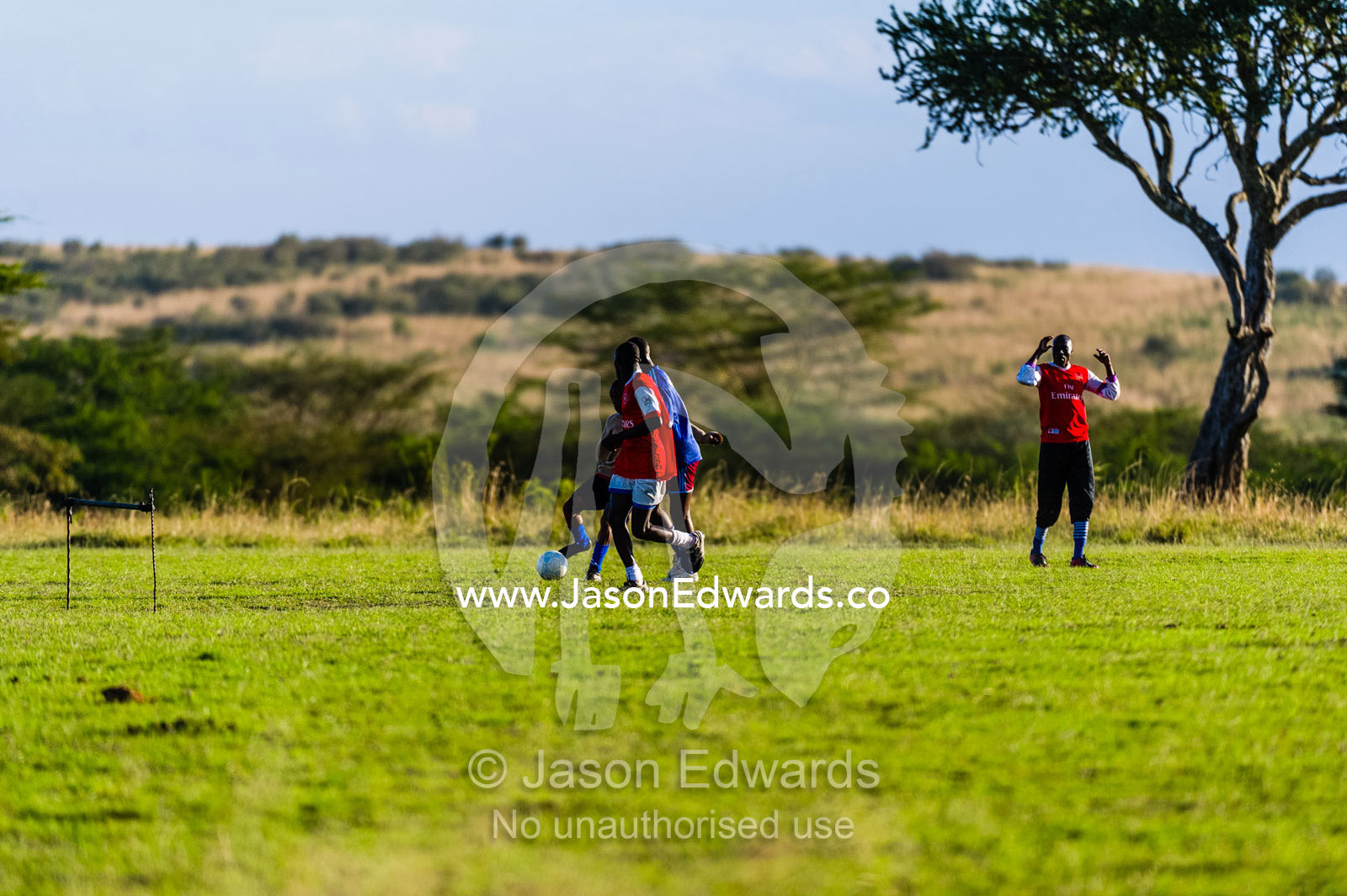 National Park rangers relaxing on their day off playing football. Maasai Mara National Reserve, Narok County, Kenya.