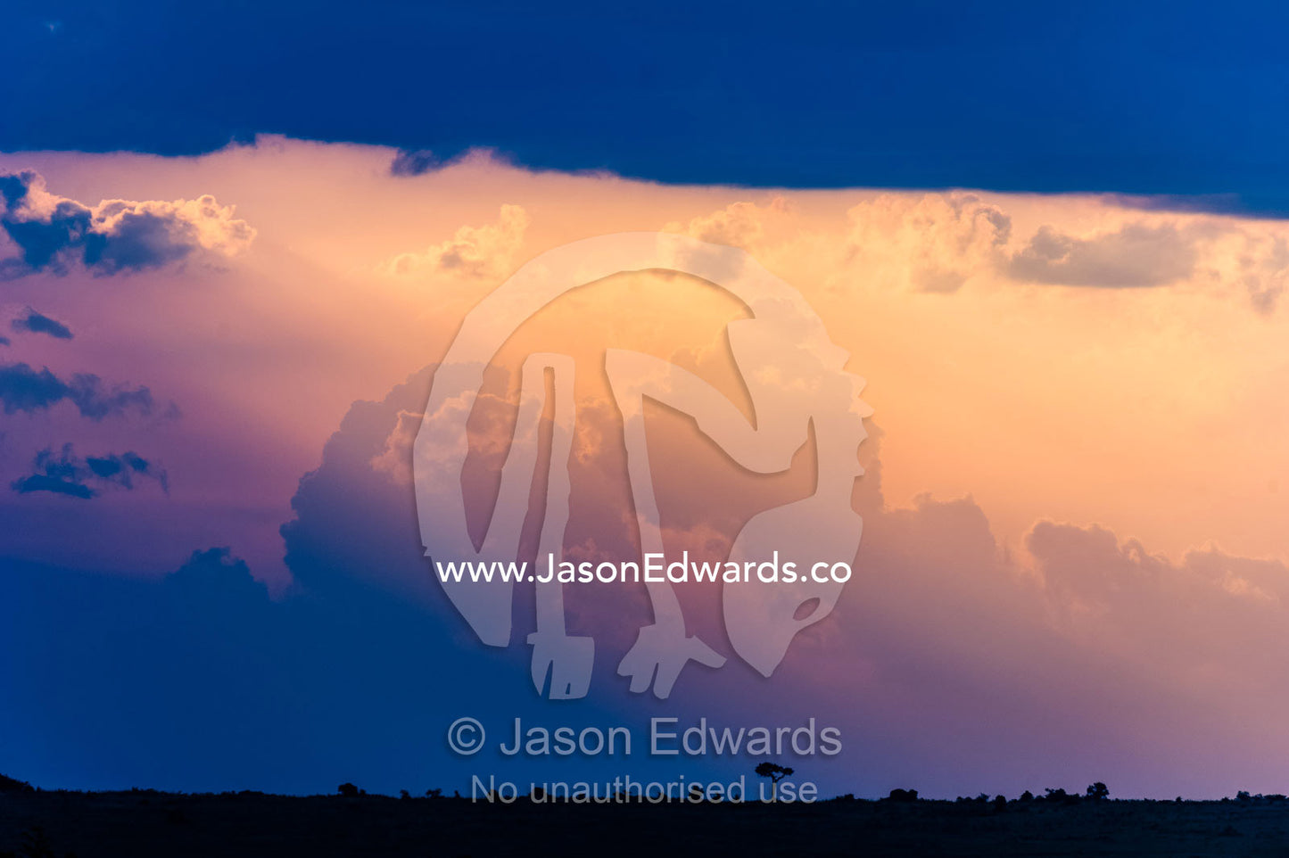 Pastel sunrays caress storm clouds descending into the horizon at sunset. Maasai Mara National Reserve, Narok County, Kenya.