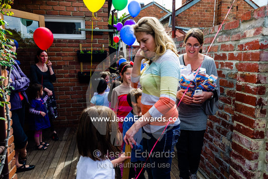 A mother at a birthday party controlling the children to hand out treat bags. Carlton North, Melbourne, Victoria, Australia.