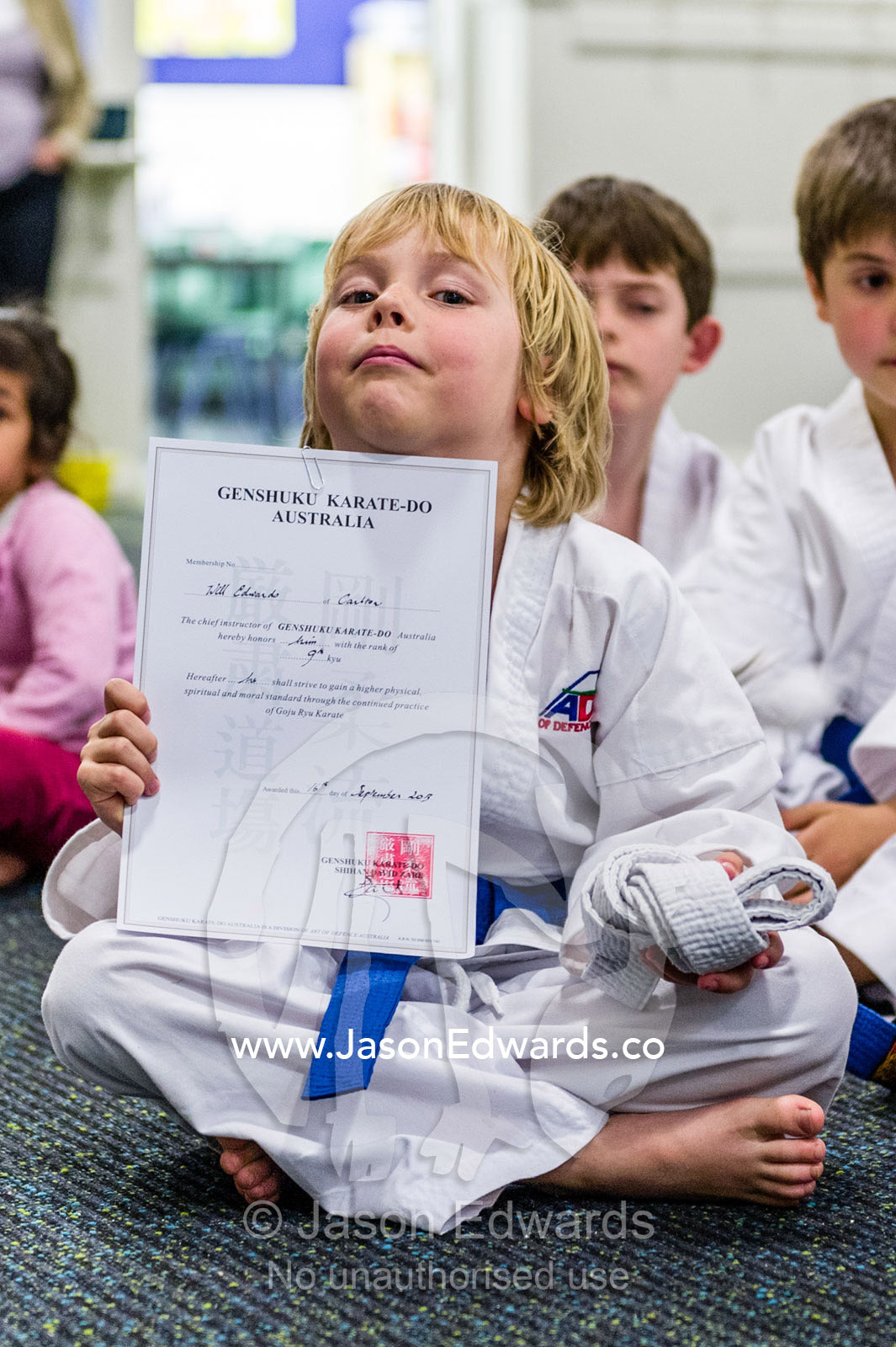 A boy displays his karate certificate awarded when he earned his blue belt. Carlton North, Melbourne, Victoria, Australia.