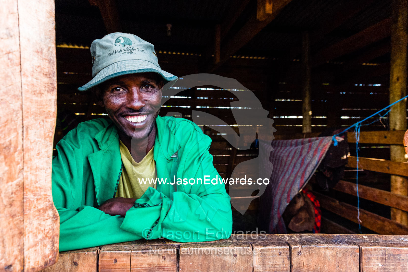 A wildlife carer sleeping in a wildlife shelter barn with an orphaned African Elephant calf. David Sheldrick Wildlife Trust, Nairobi, Kenya.