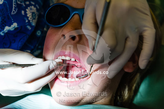 A dentist uses a sickle probe and a mirror to examine a boys teeth. East Melbourne, Melbourne, Victoria, Australia.