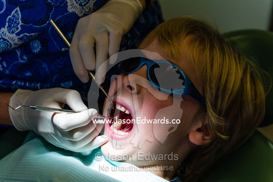 A dentist uses a sickle probe and a mirror to examine a boys teeth. East Melbourne, Melbourne, Victoria, Australia.