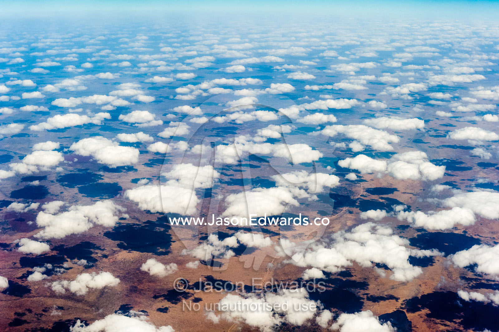 A flotilla of white fluffy clouds casting shadows onto a vast desert plain. Over South-eastern Ethiopia.