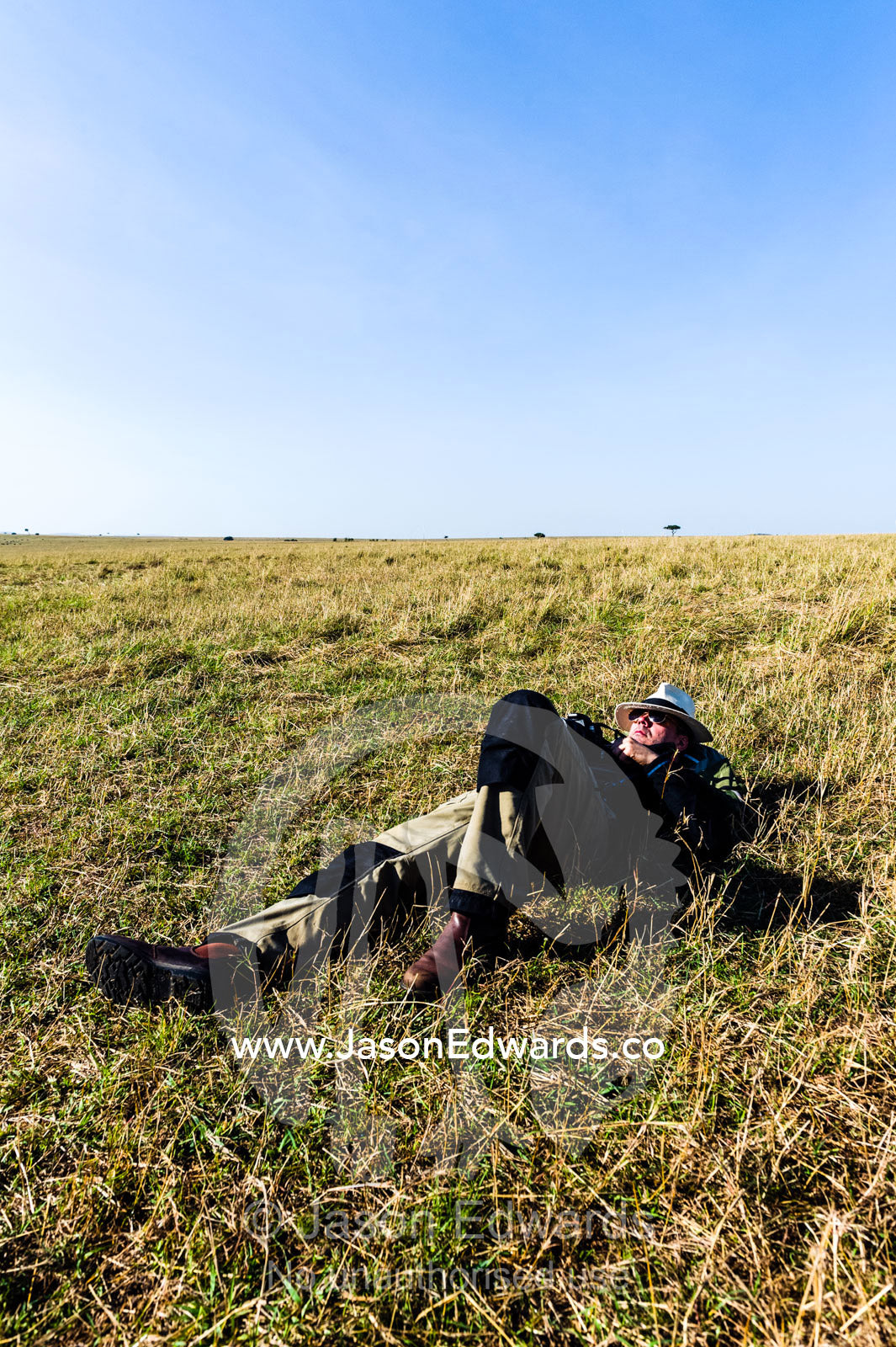 A tourist sleeping on the African savannah after a morning of hot air ballooning, game driving and breakfast. Maasai Mara National Reserve, Masai Mara, Narok County, Kenya.