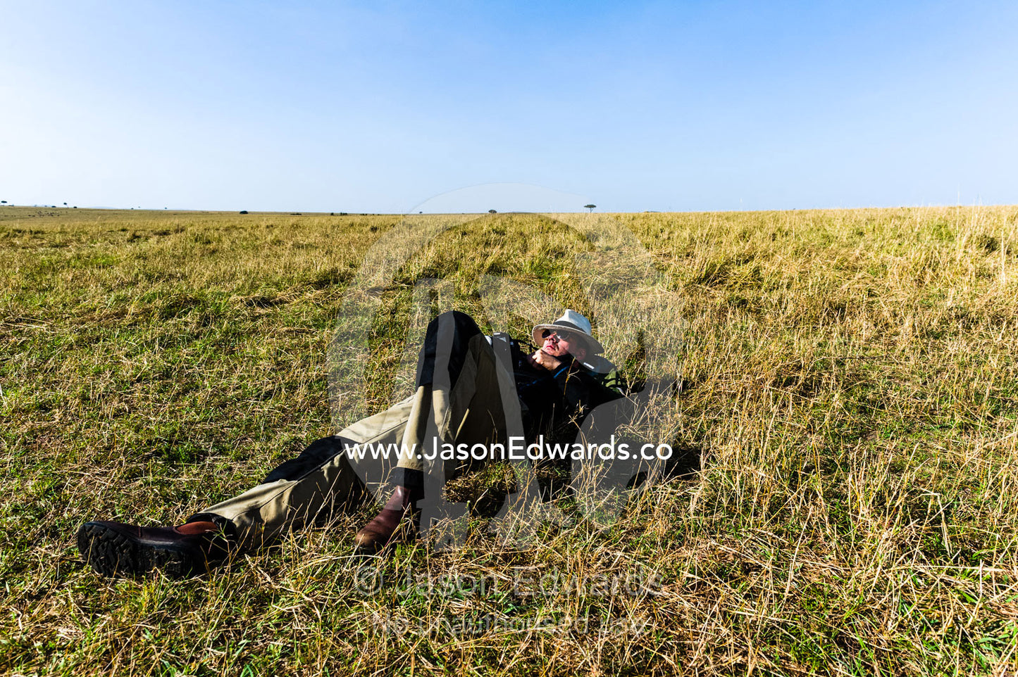 A tourist sleeping on the African savannah after a morning of hot air ballooning, game driving and breakfast. Maasai Mara National Reserve, Masai Mara, Narok County, Kenya.