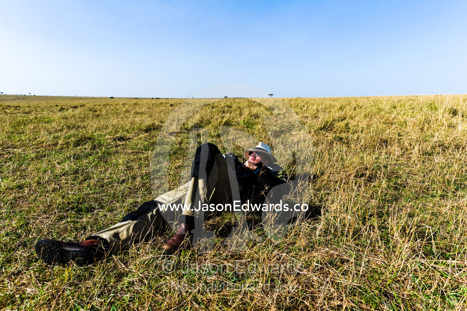 A tourist sleeping on the African savannah after a morning of hot air ballooning, game driving and breakfast. Maasai Mara National Reserve, Masai Mara, Narok County, Kenya.