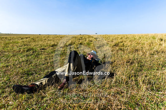 A tourist sleeping on the African savannah after a morning of hot air ballooning, game driving and breakfast. Maasai Mara National Reserve, Masai Mara, Narok County, Kenya.