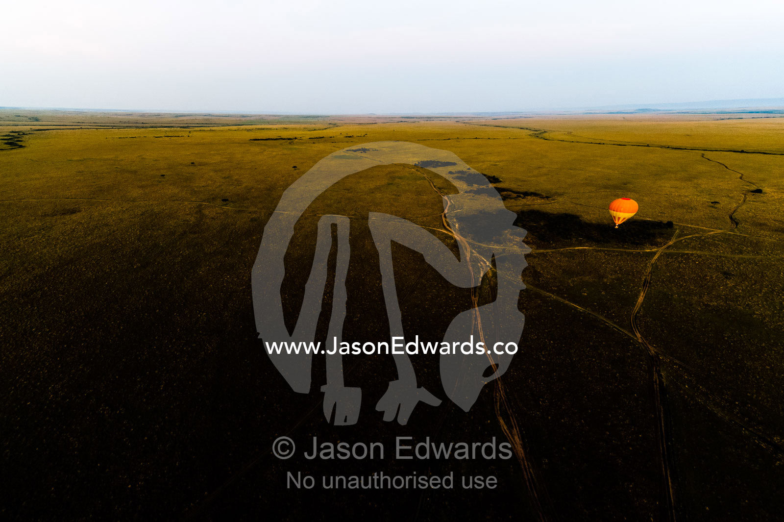 A hot air balloon floating over the vast short grass plains of the African savannah. Maasai Mara National Reserve, Masai Mara, Narok County, Kenya.