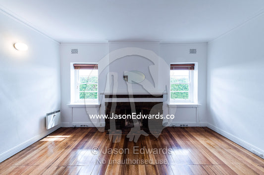 A living room and fireplace above polished floorboards in an empty rental apartment freshly painted in white. St Kilda Road, Melbourne, Victoria, Australia.