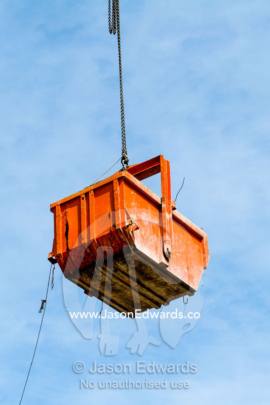 A crane lifts a steel bucket removing rubble from a building destroyed in an earthquake. Christchurch, South Island, New Zealand.