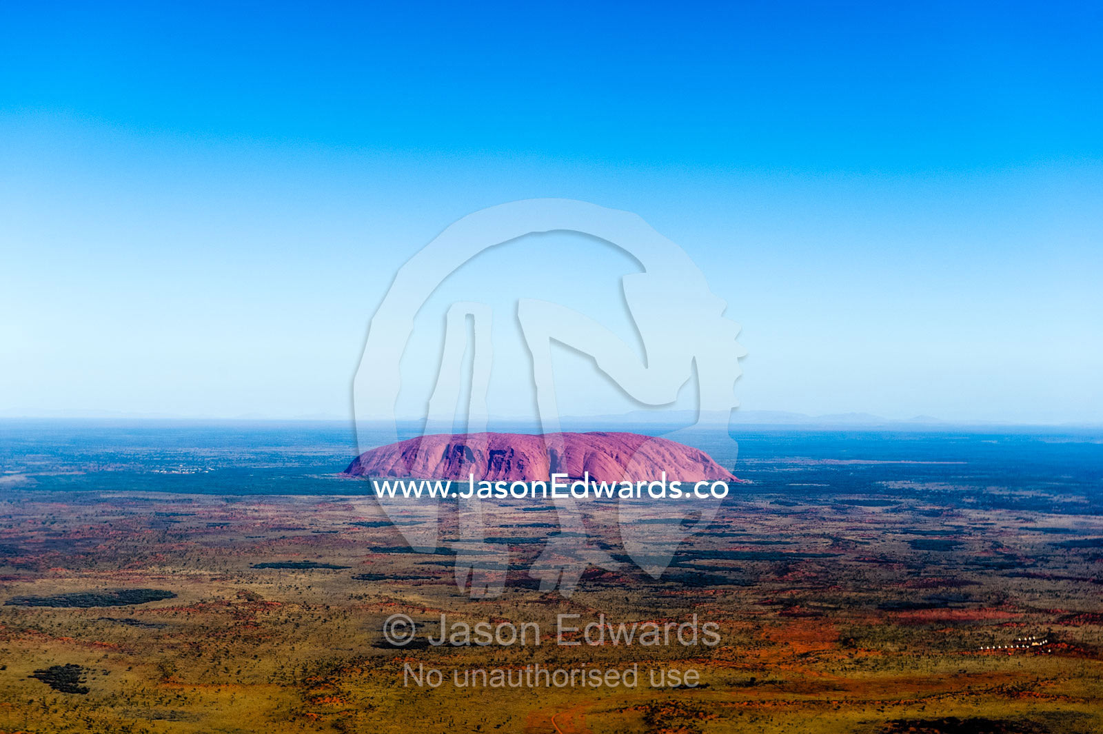 The ochre sandstone dome of Uluru rises from a vast desert plain in Australia's Outback. Uluru Kata Tjuta National Park, Northern Territory, Australia.