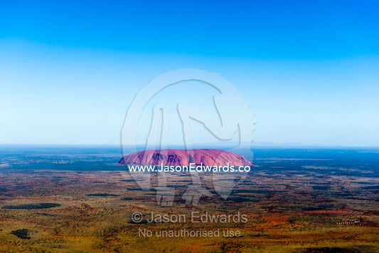 The ochre sandstone dome of Uluru rises from a vast desert plain in Australia's Outback. Uluru Kata Tjuta National Park, Northern Territory, Australia.