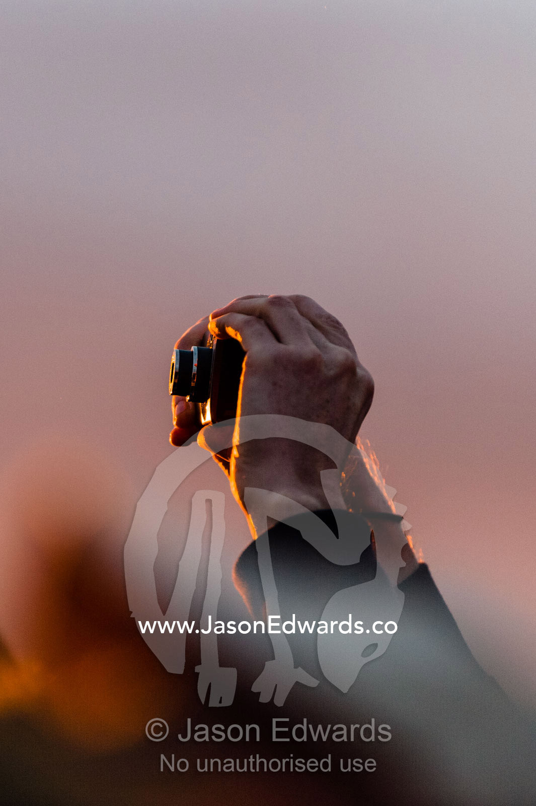 A tourist holds his digital camera above a crowd to capture the sunrise over the desert and Uluru. Uluru Kata Tjuta National Park, Northern Territory, Australia.