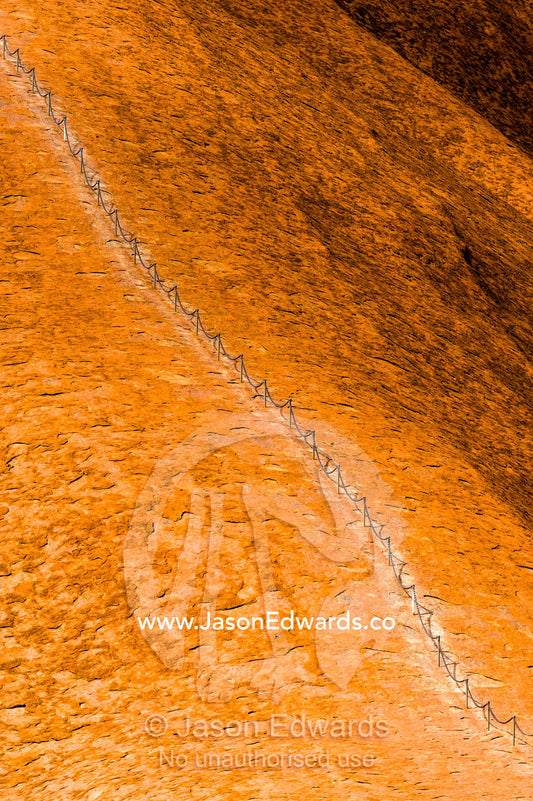 A chain assists tourists and walkers to climb the steep, smooth slope of Uluru. Uluru Kata Tjuta National Park, Northern Territory, Australia.