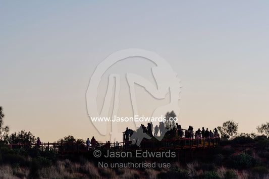 The silhouette of tourists gathered in the chill dawn light to watch dawn at Uluru. Uluru Kata Tjuta National Park, Northern Territory, Australia.