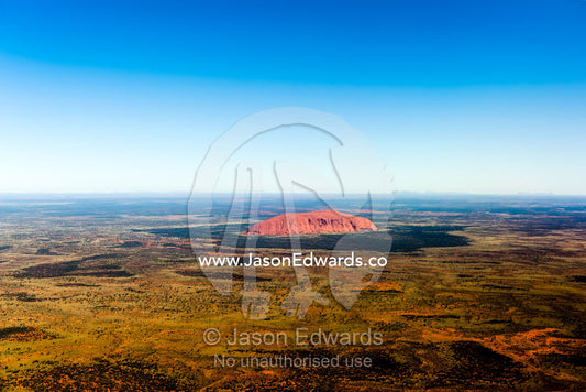 The ochre sandstone dome of Uluru rises from a vast desert plain in Australia's Outback. Uluru Kata Tjuta National Park, Northern Territory, Australia.