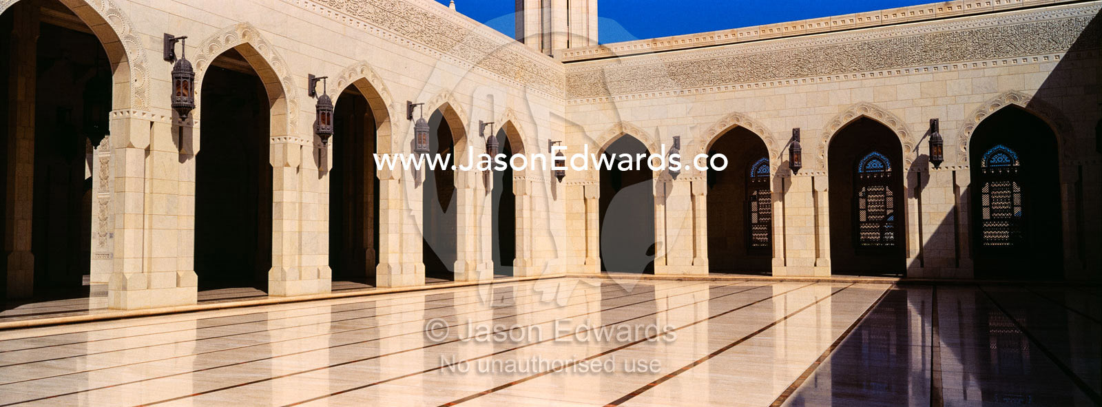 Sandstone archways surround a polished courtyard in the Grand Mosque. Sultan Qaboos Grand Mosque, Muscat, Sultanate of Oman.