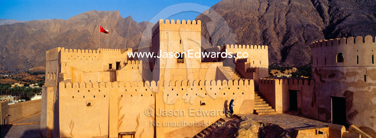 The ancient walls, parapets, battlements and watch tower of a fort on a desert mountaintop. Nakhal Fort, Wilayt Nakhal, Mount Nakhal, Al Batinah South Governorate, Sultanate of Oman.