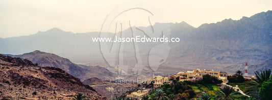 A village perched on a mountaintop overlooking an arid desert valley. Wakan Village, Wadi Mastal, Wilayt Nakhal, Al Batinah South Governorate, Sultanate of Oman.