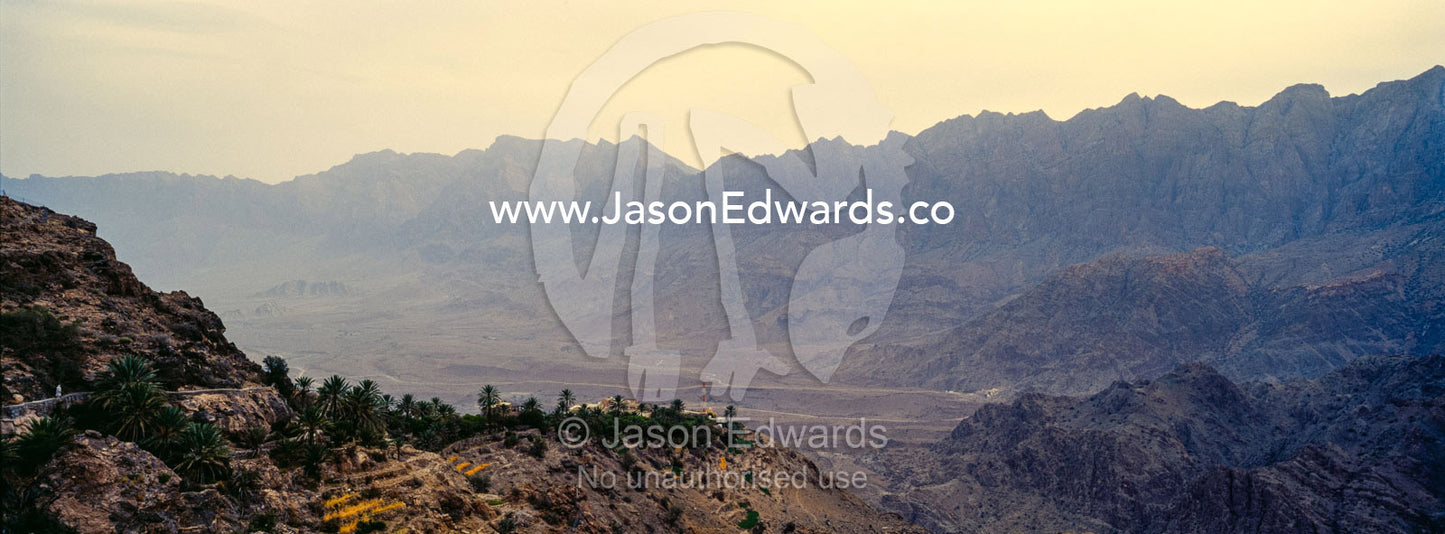 A village perched on a mountaintop overlooking an arid desert valley. Wakan Village, Wadi Mastal, Wilayt Nakhal, Al Batinah South Governorate, Sultanate of Oman.
