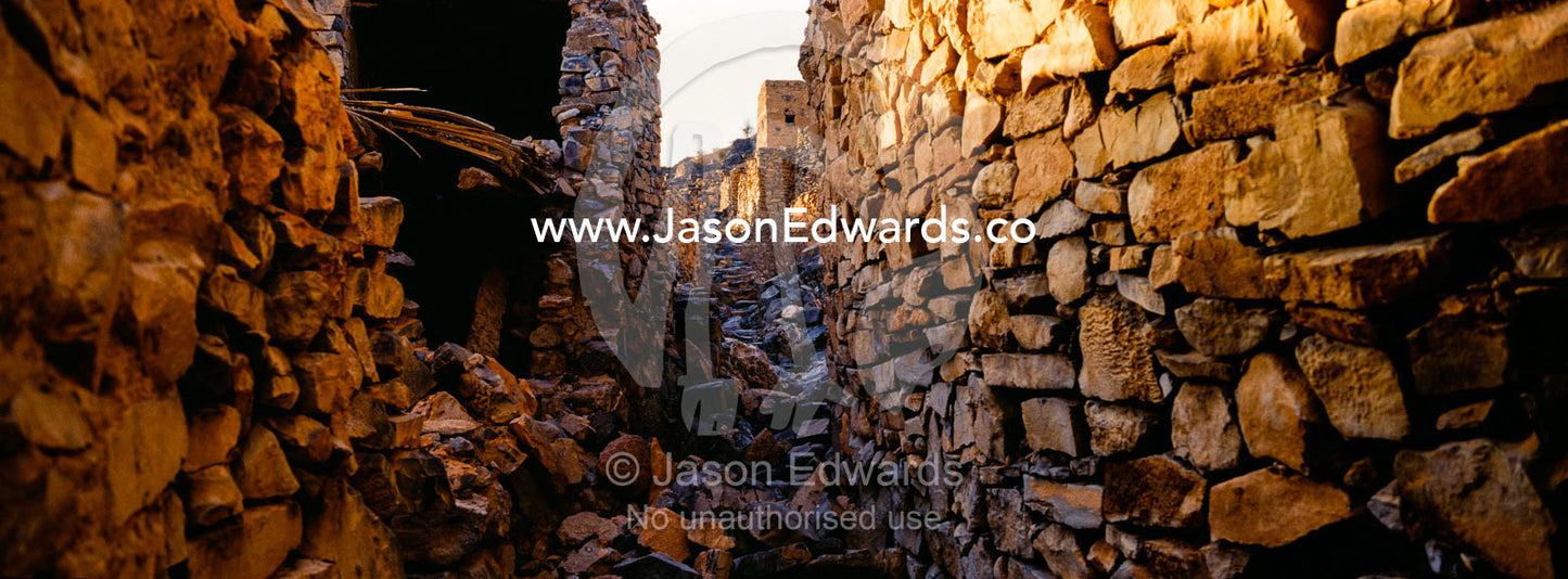 Ancient handmade stone buildings, shops and homes line a street in an abandoned village. Wadi Nakhar, Al Hamra, Ad Dakhiliyah Region, Sultanate of Oman.