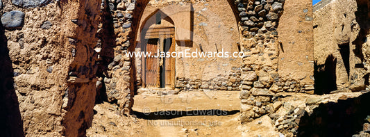 Crumbling walls and market archways collapse back into the desert in an ancient abandoned village. Ibra, Ash Sharqiyah Region, Sultanate of Oman.