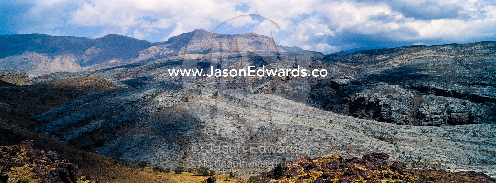 The arid rocky slopes of a prehistoric and volcanic desert landscape. Jebel Shams, Al Hajar Mountains, Sultanate of Oman.