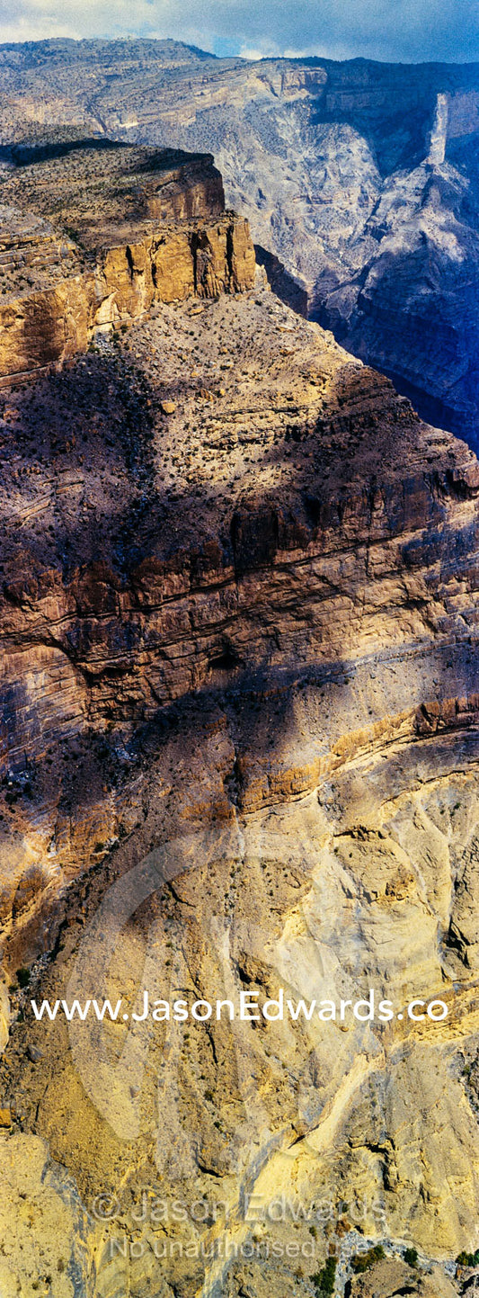 Sheer cliff walls and terraces carved by erosion in a massive desert canyon. Wadi Ghul, Jebel Shams, Al Hajar Mountains, Sultanate of Oman.