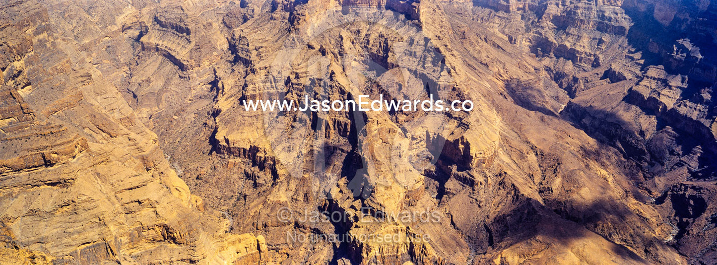 Sheer cliff walls and terraces carved by erosion in a massive desert canyon. Wadi Ghul, Jebel Shams, Al Hajar Mountains, Sultanate of Oman.