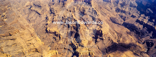 Sheer cliff walls and terraces carved by erosion in a massive desert canyon. Wadi Ghul, Jebel Shams, Al Hajar Mountains, Sultanate of Oman.