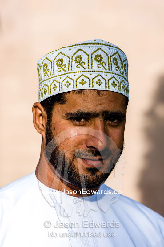 A handsome and happy smiling Muslim man wearing a traditional kuma. Sultan Qaboos Grand Mosque, Muscat, Sultanate of Oman.