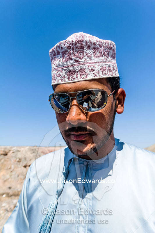 A man from Oman wearing a turban known as a masar, sunglasses and a dishdasha. Muscat, Sultanate of Oman.